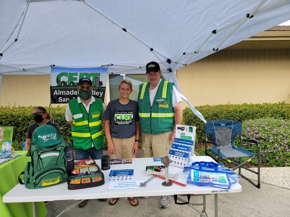 At an event, Citizen emergency response team members are posing behind their community outreach table.